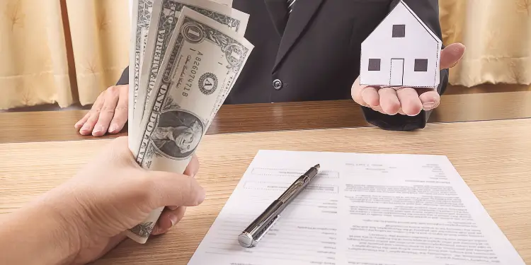 Hand exchanging cash for a paper house over a lease contract, illustrating renewal options.