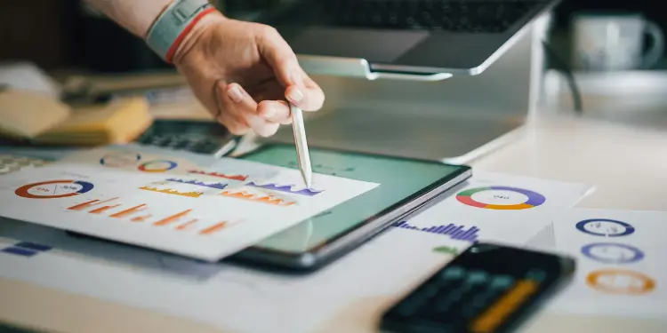 Person’s hand using a stylus to interact with expense charts on a tablet amid reports.