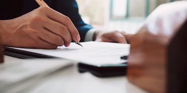 Close-up of hands writing on papers with pen representing documentation work