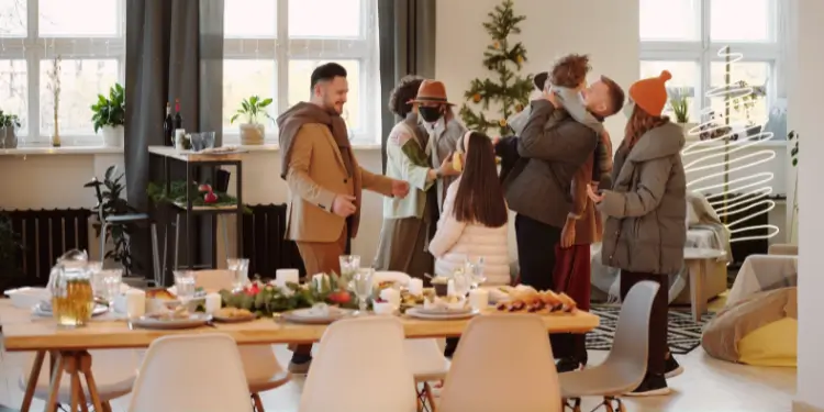 People gathered indoors for a festive event with a Christmas tree and holiday decorations.