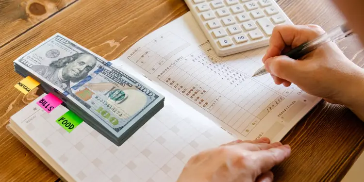 Ledger and cash stack illustrating monthly budget tracking and reallocation of surplus funds.