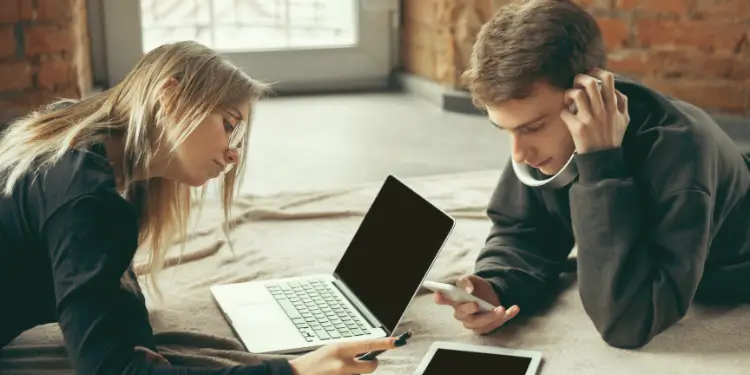 College students studying with laptops and smartphones, highlighting renters insurance.