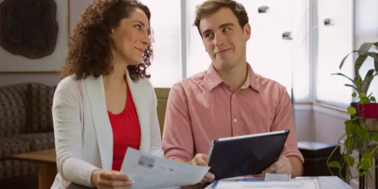 Spouses consult health coverage details on documents and a tablet, safeguarding finances.