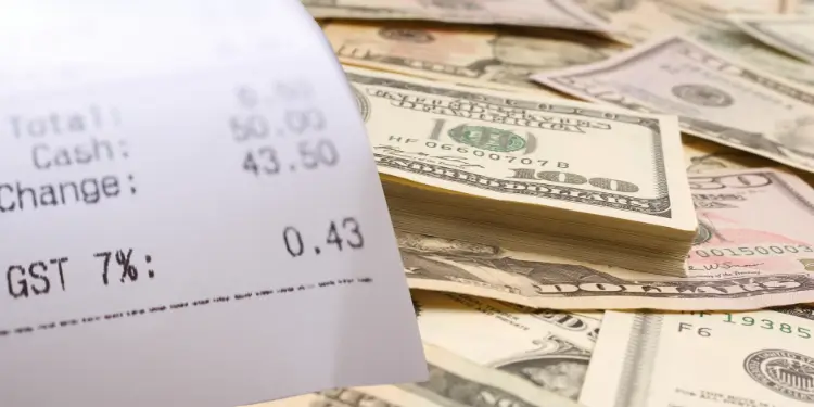 Close-up of printed receipt laying on US currency to signify cash record reconciliation.
